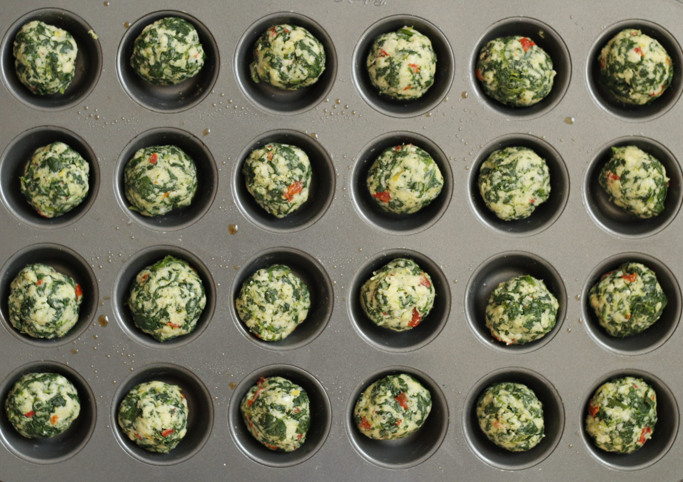 A detail shot showing a close-up of collard green balls on a muffin tray. 
