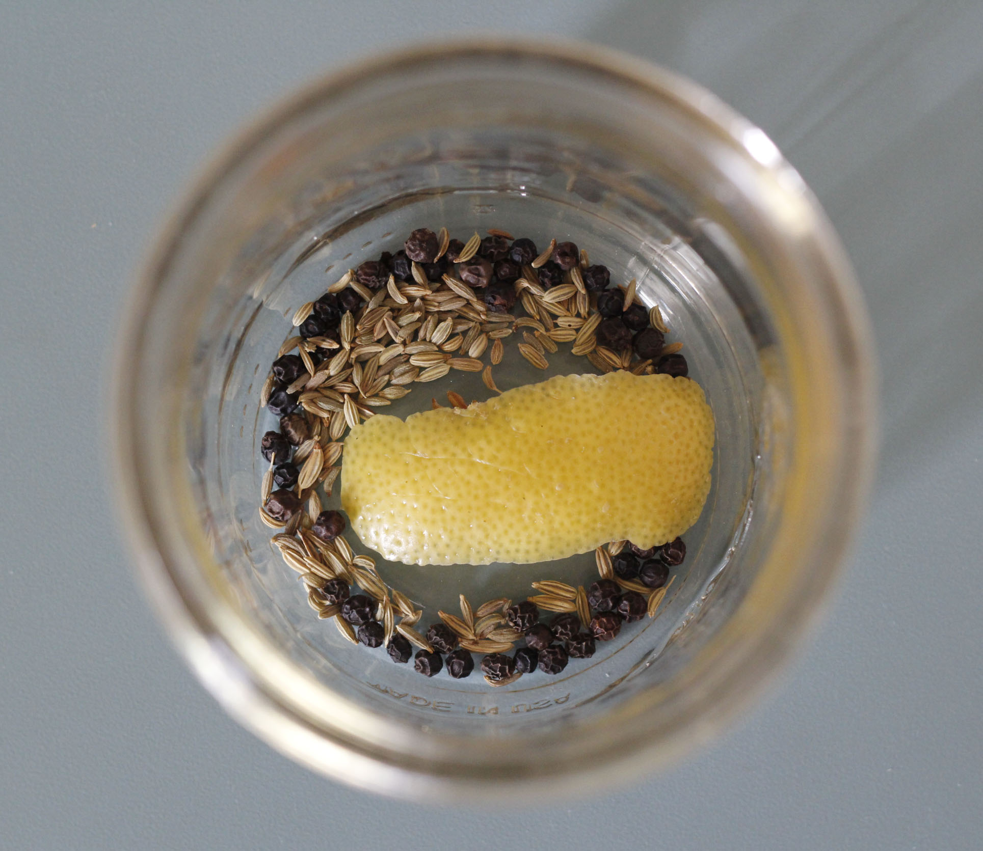 Fennel seeds, peppercorns, and lemon peels in a Mason Jar for pickling Kohlrabi.