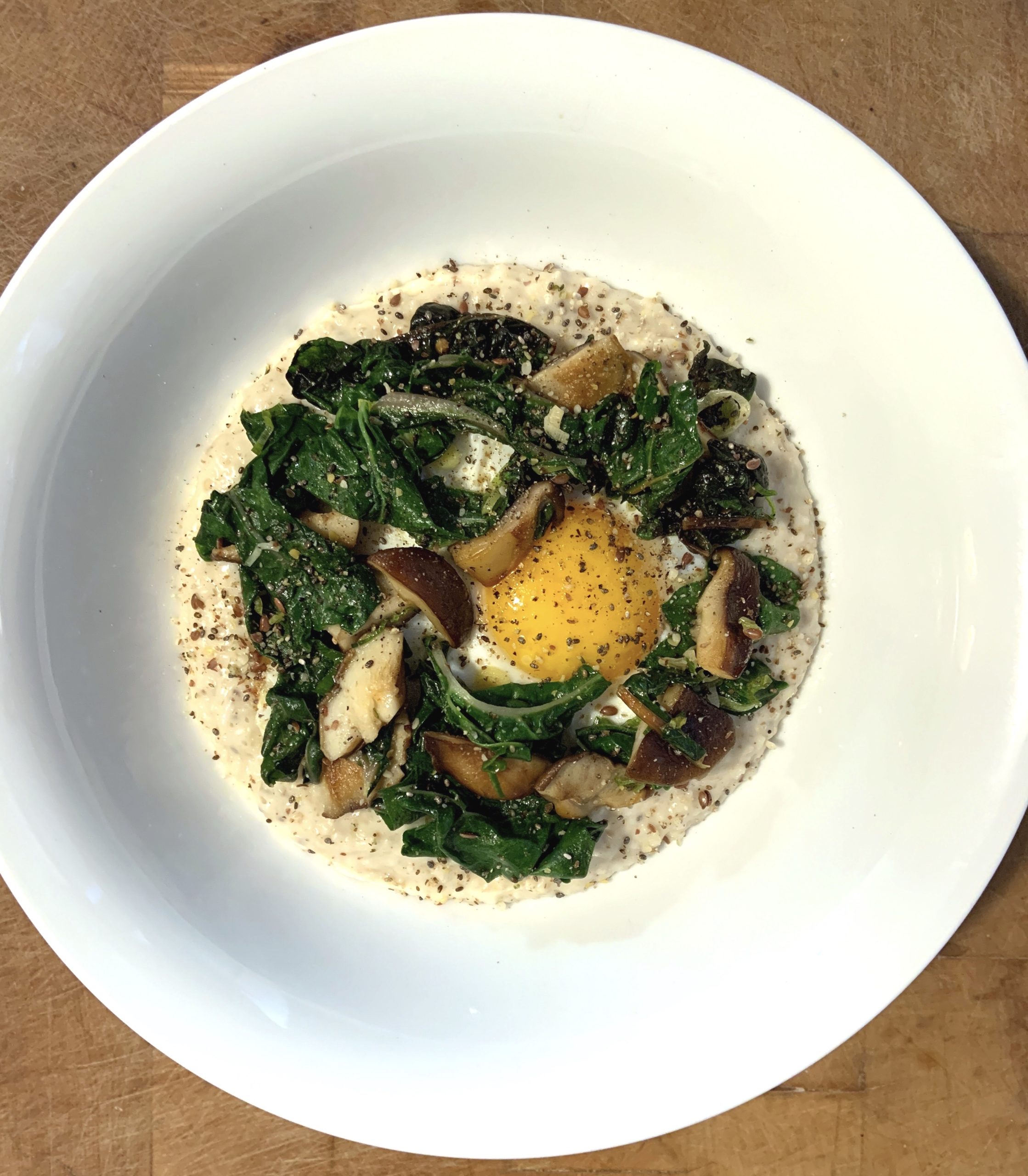 An overhead shot of Oats with Swiss Chard, Shiitake Mushrooms and a Fried Egg. Recipe by Michael Joyce with Taproot Farm, PA.