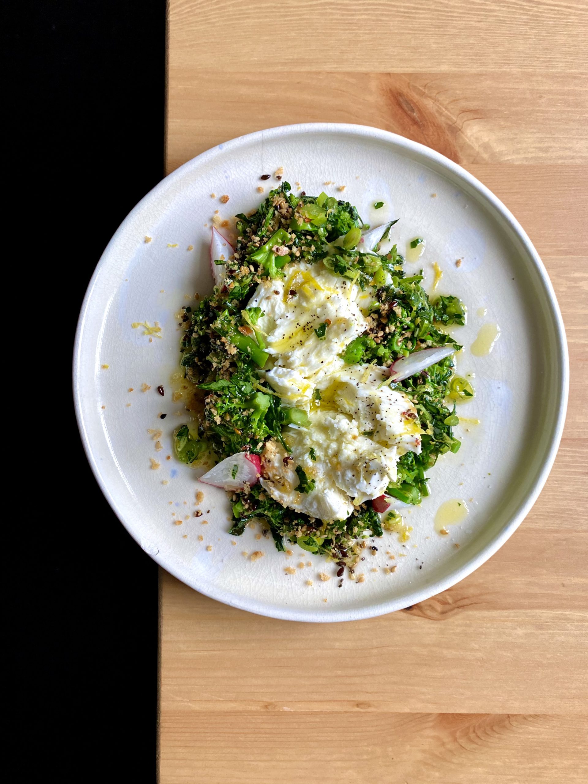 A plate of sprouting broccoli with fresh mozzarella, green garlic oil, and everything breadcrumbs.