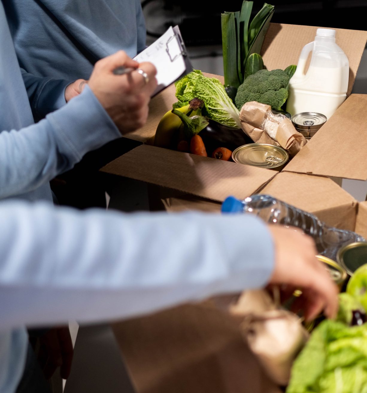 People sorting through fresh food in boxes.